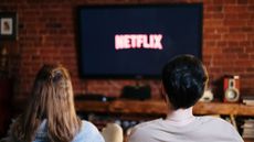 Couple watching Netflix logo on TV