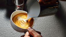 A person doing latte art in a white cup 